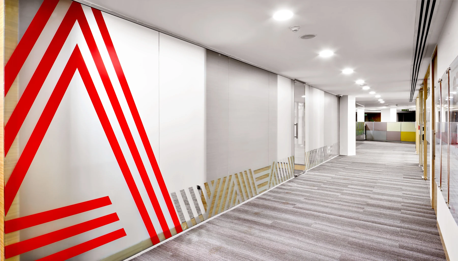 Red geometric wall graphic along an office corridor.