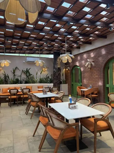 Dining area with orange cushions and green arches beneath a canopy.