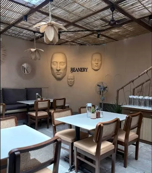 Woven pendants above dining, with sculpted-face artwork and the café logo.