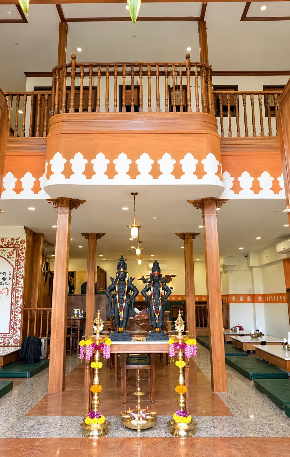 Double-height Purnabramha dining interior with a central display, timber columns and upper railing.