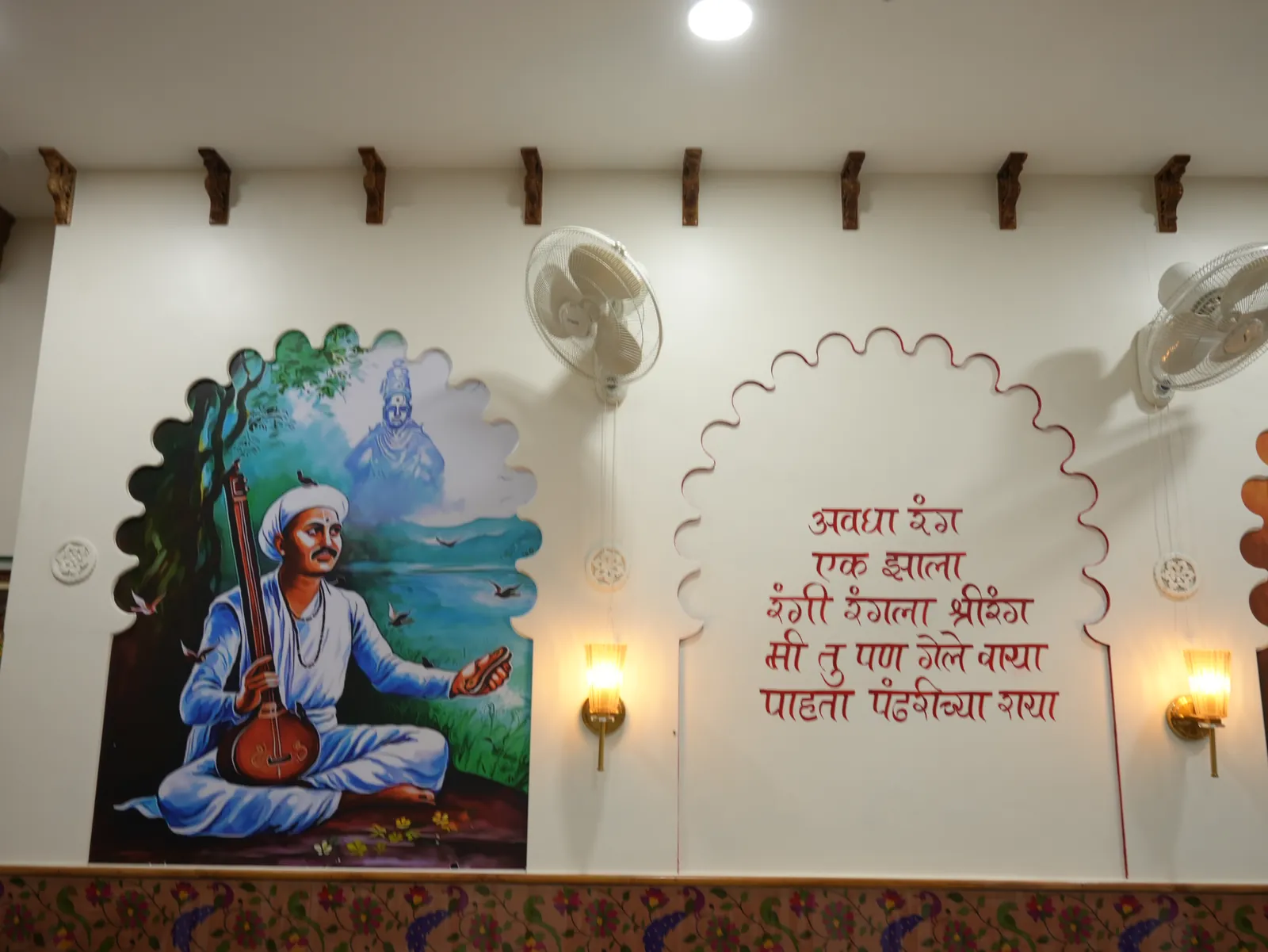 Seated musician artwork beside Marathi lettering and lamps.