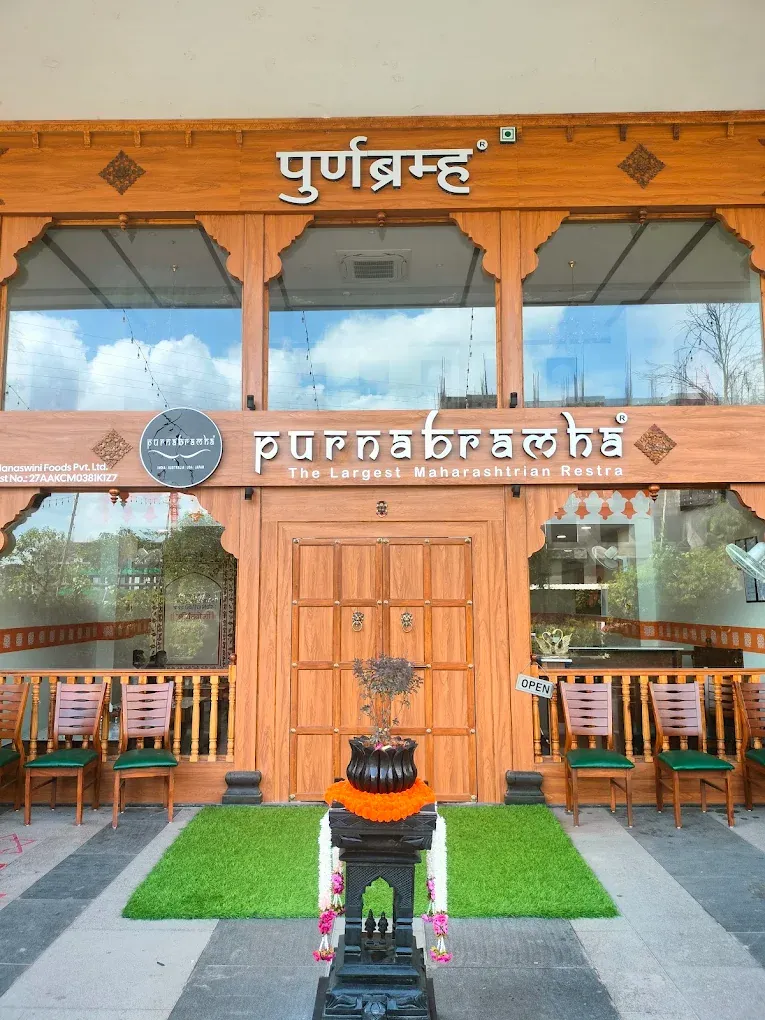 Front entrance with wooden doors, signage and chairs.