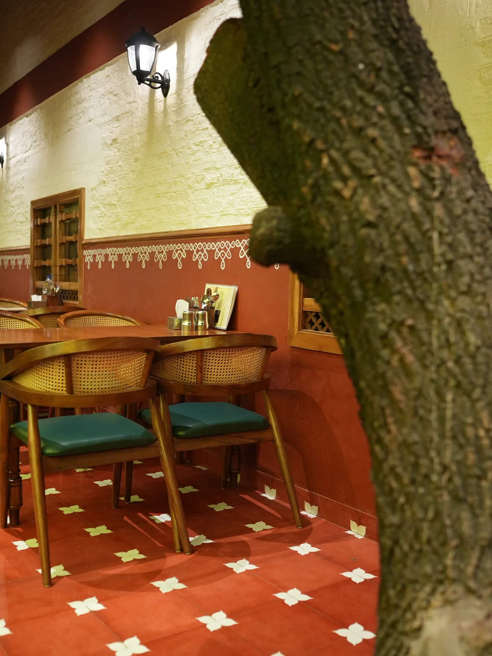 Dining tables beside a tree trunk with a red-and-white patterned floor.