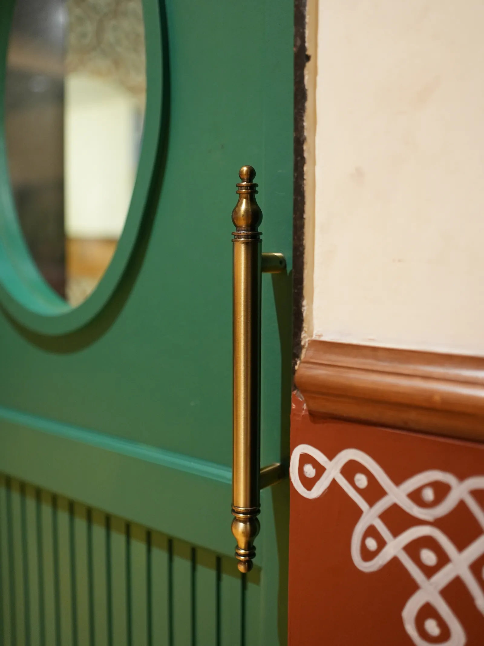 Green door beside a white pattern on a red wall.