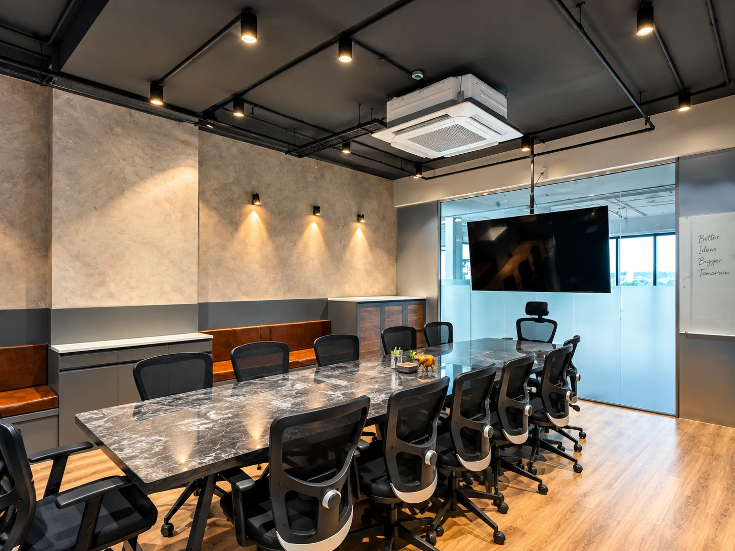 Meeting room with a long table, dark ceiling, grey finishes and glazed partition.