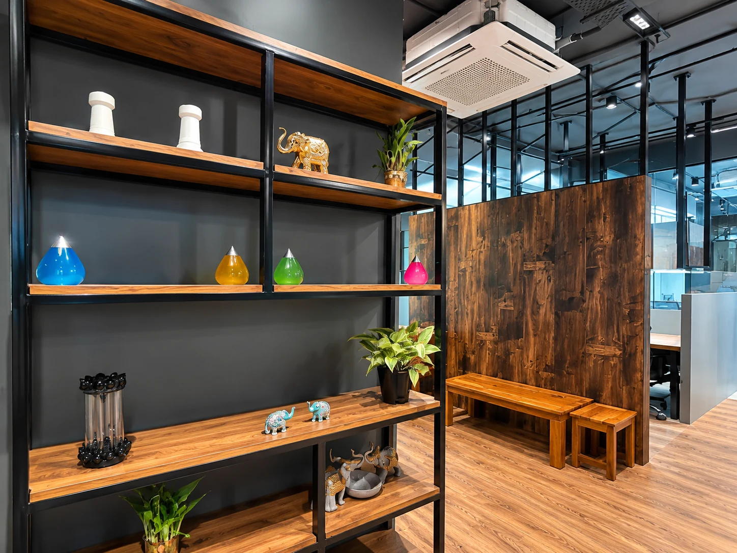 Open shelving with small objects and planting beside a wood-toned bench.